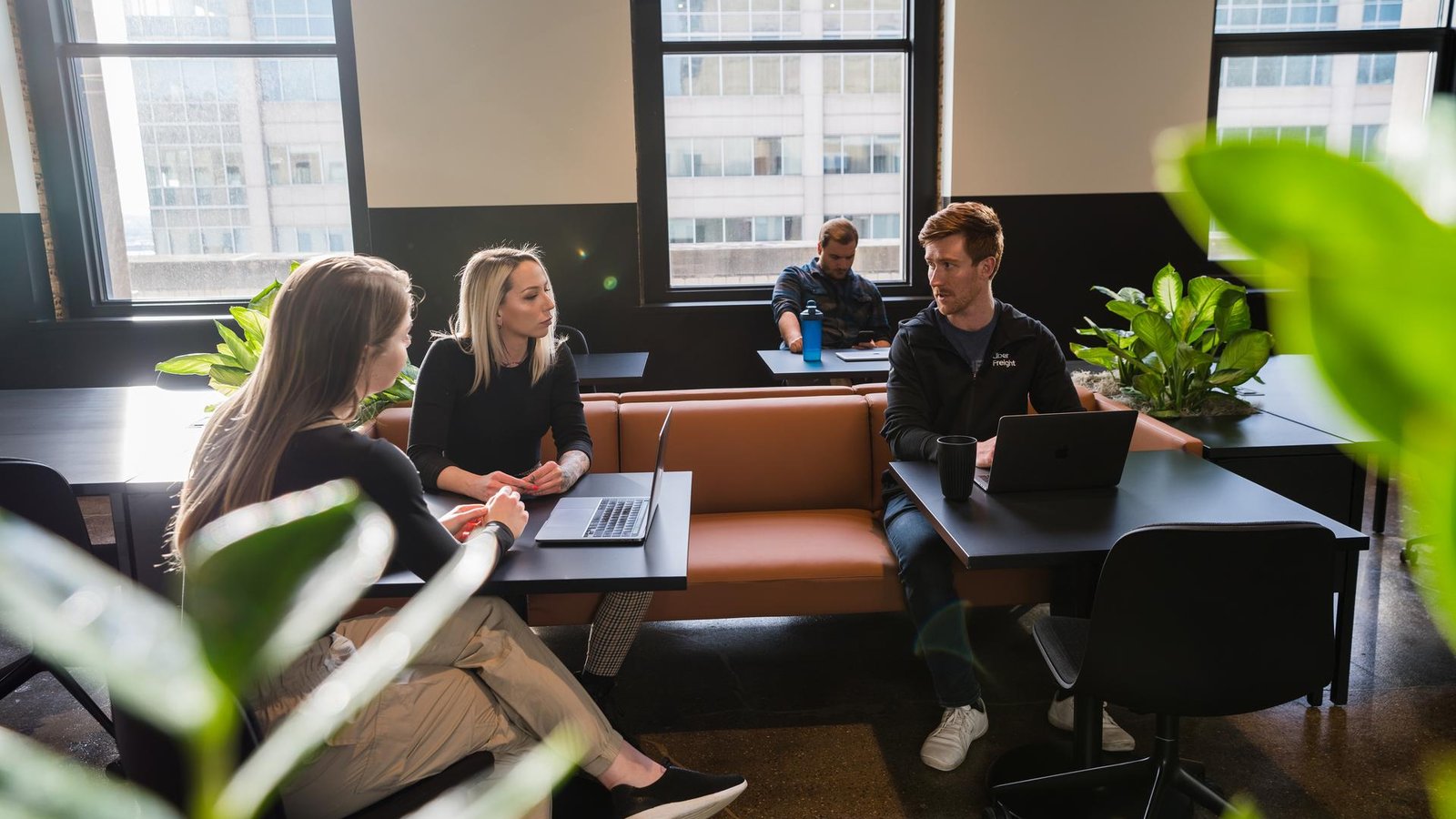 a group of people sitting at tables with laptops