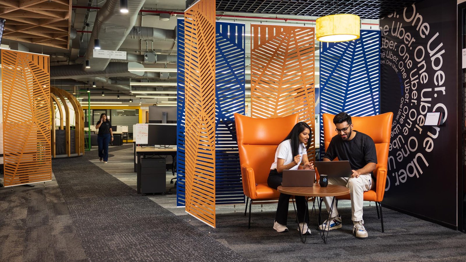 a person and person sitting in an orange chair with a laptop