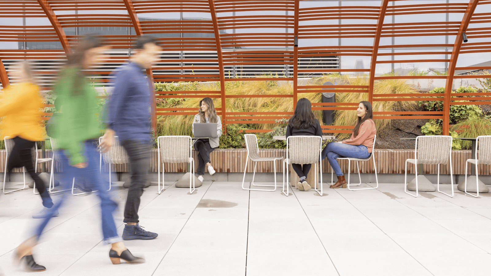 people sitting on chairs in a room with a glass roof