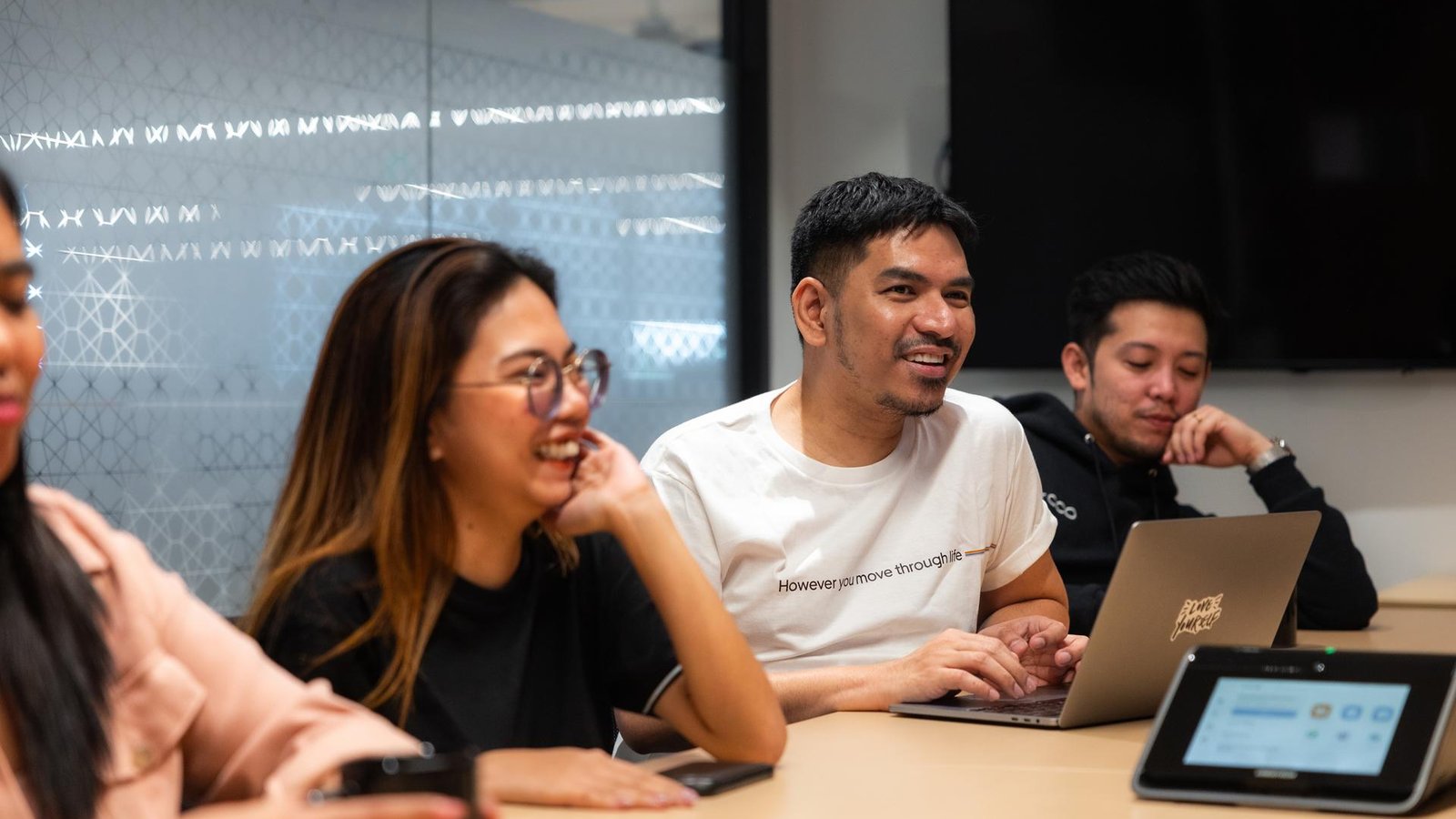 a group of people sitting at a table with laptops