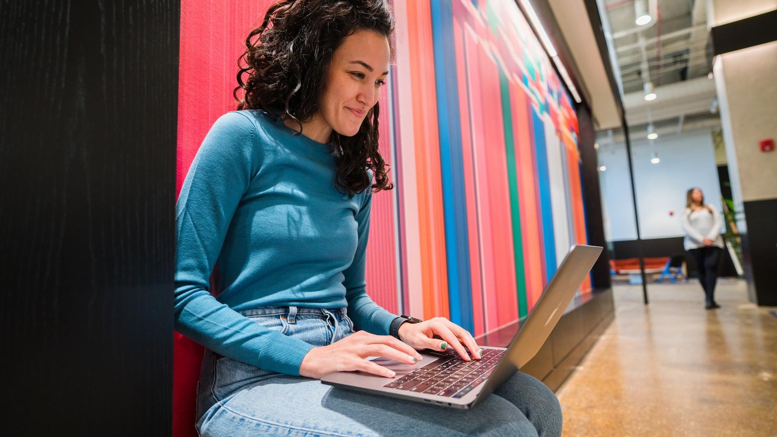 a person sitting on a bench using a laptop