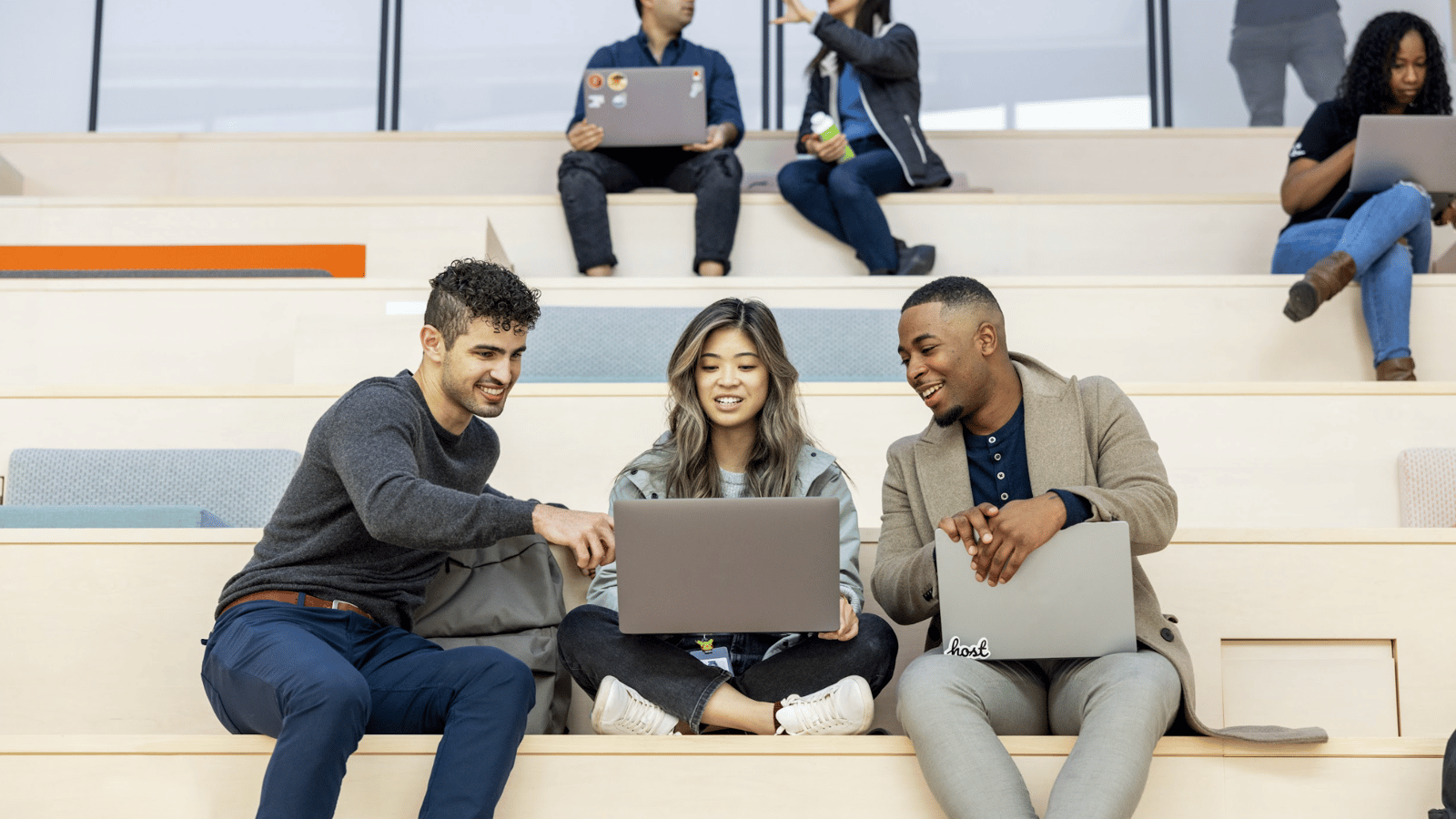 a group of people sitting on stairs with laptops