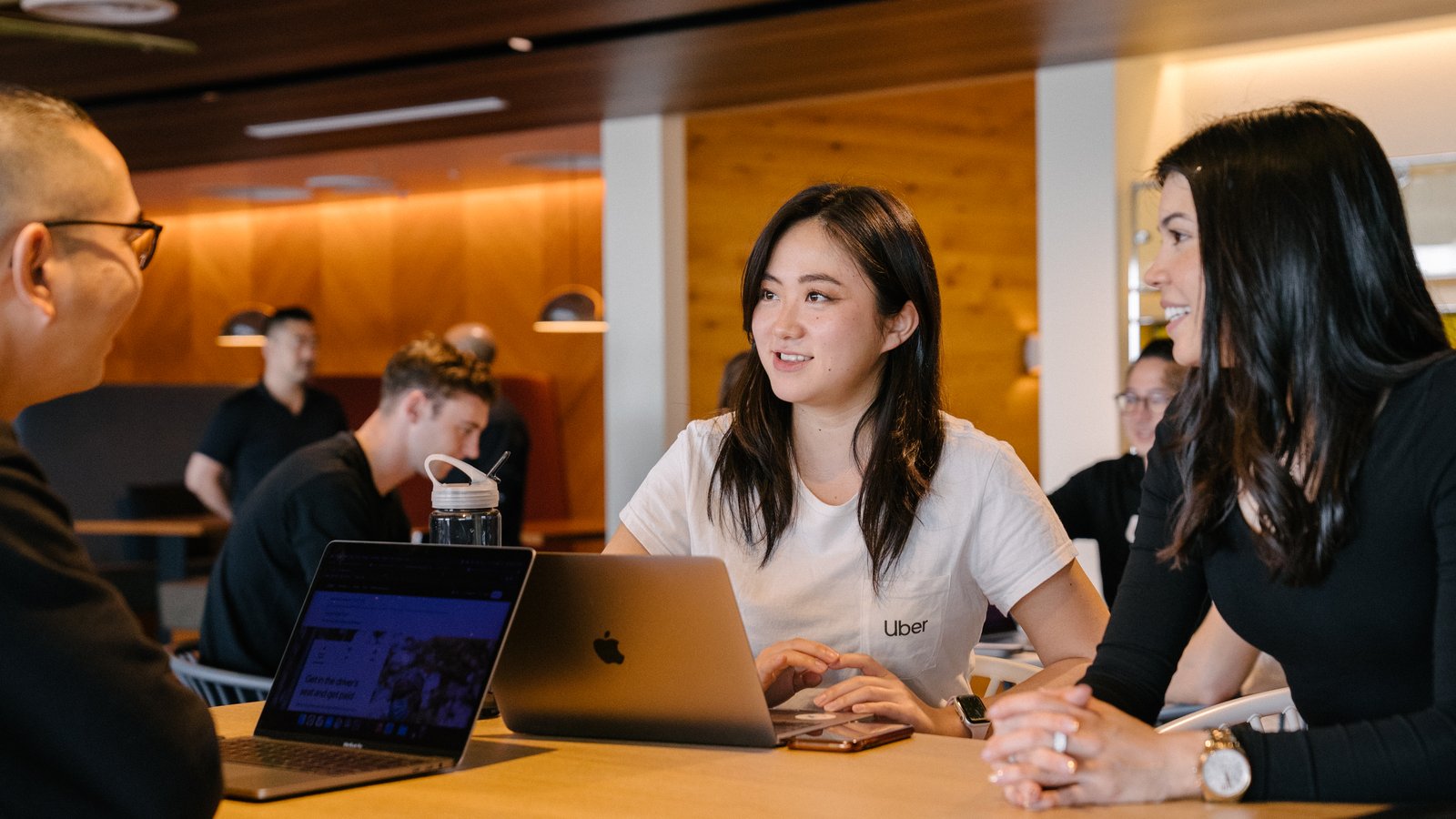 a group of people sitting at a table with laptops