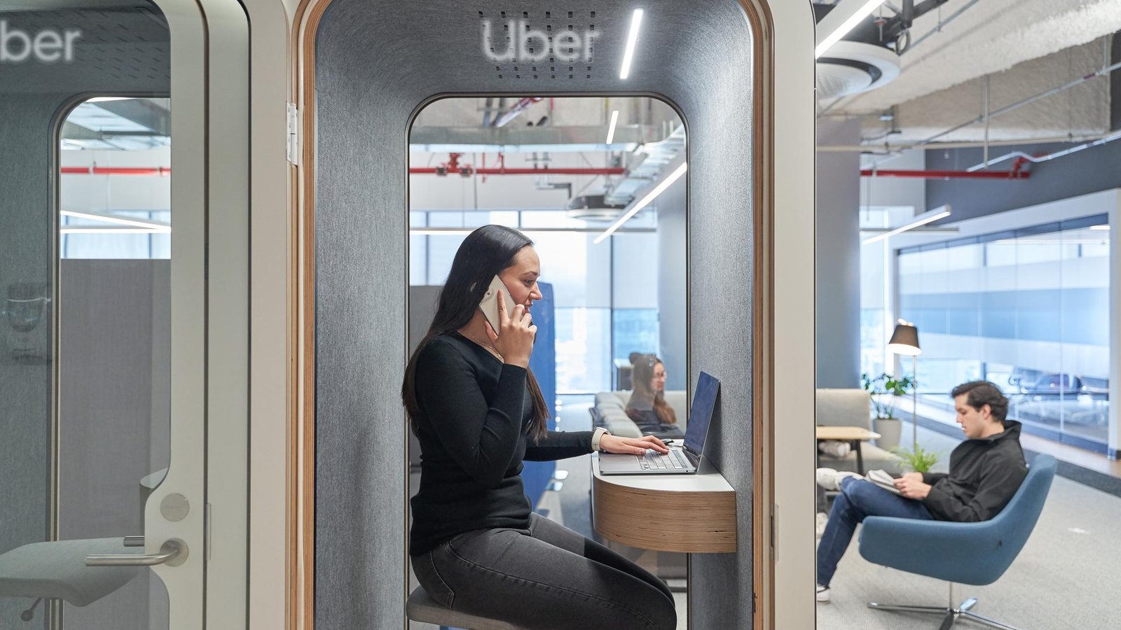 a person sitting at a desk with a laptop and phone on her ear