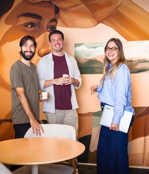 a group of people standing in a room with a mural of a person