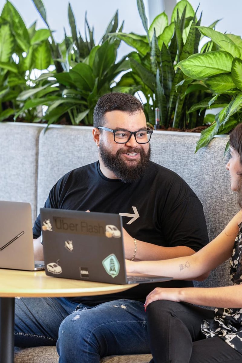 a person and person sitting at a table with laptops