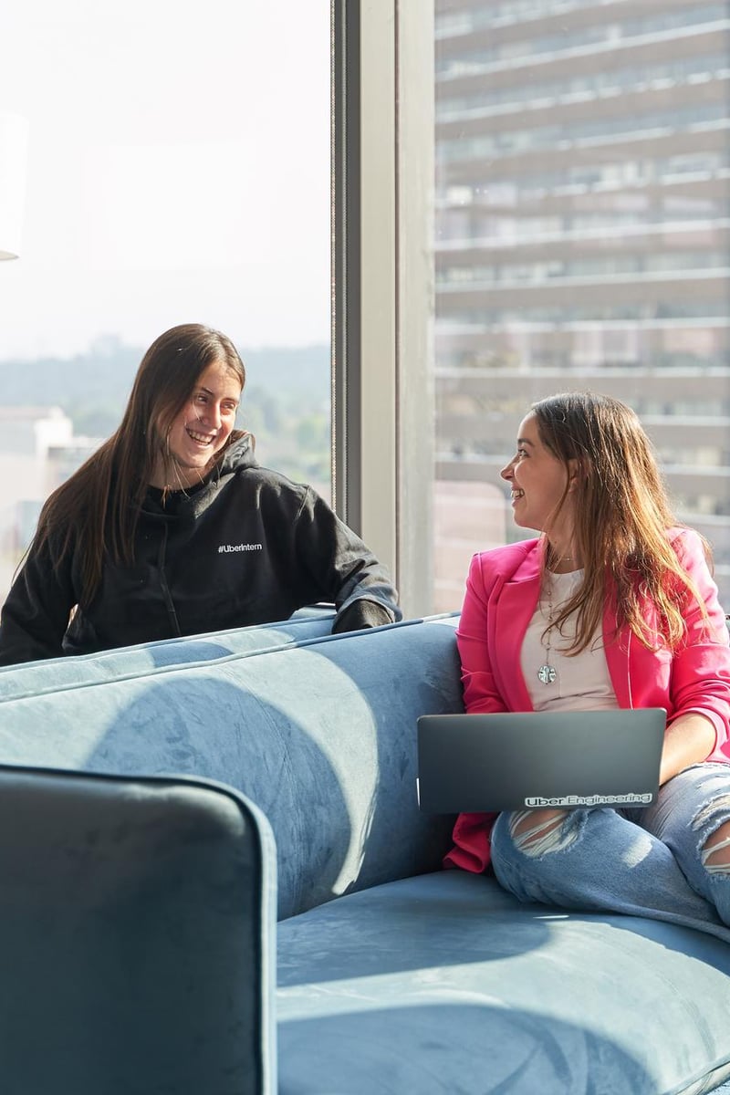 two women sitting on a couch looking at each other