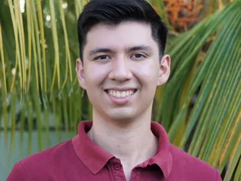 a person smiling in front of a palm tree
