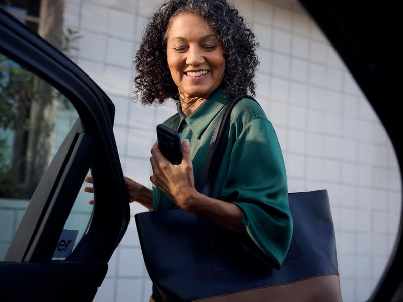a person holding a phone and looking at her car door