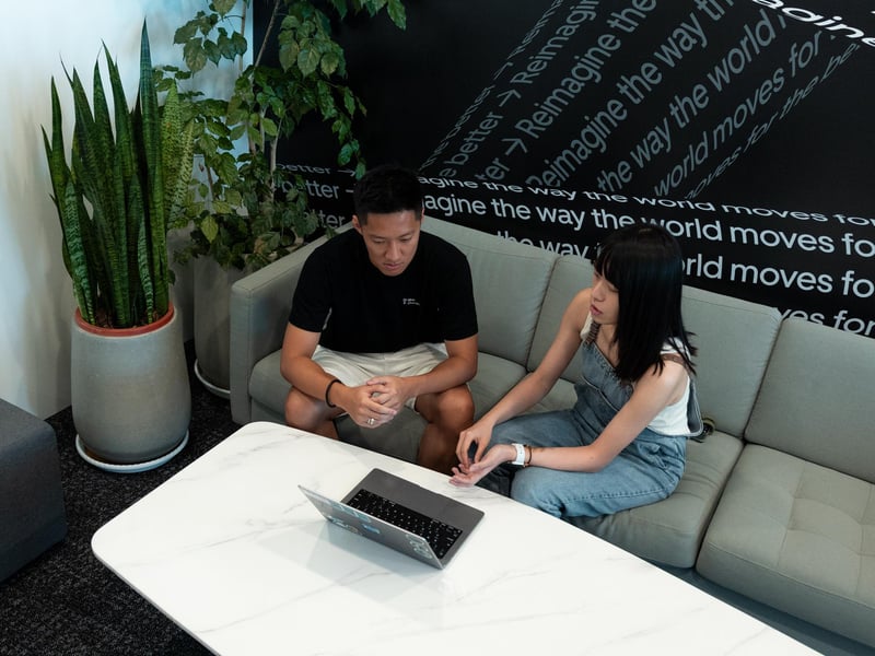 a person and person sitting on a couch looking at a laptop