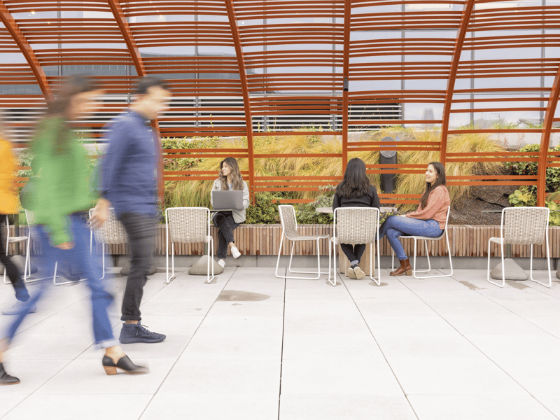 people sitting on chairs in a room with a glass roof