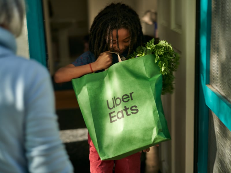 a person holding a green bag with vegetables