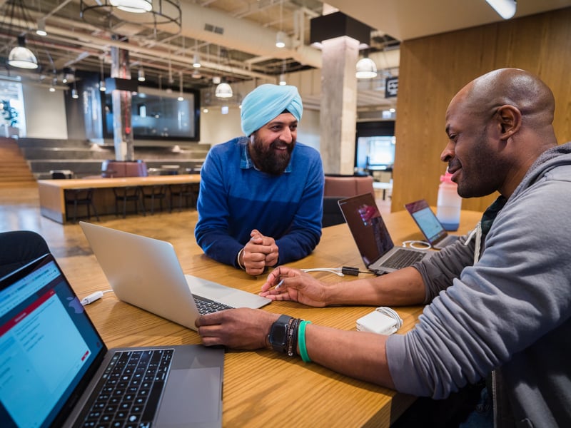 a group of men sitting at a table with laptops