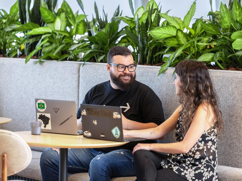 a person and person sitting at a table with laptops