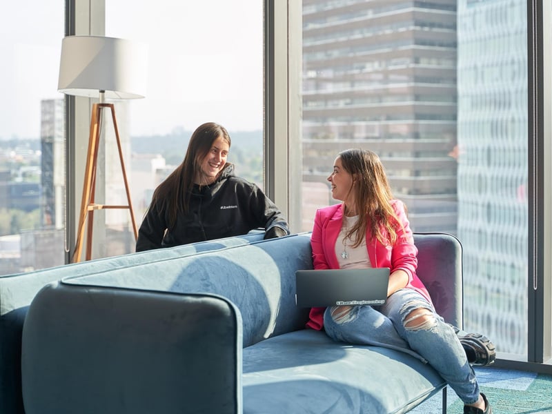 two women sitting on a couch looking at each other