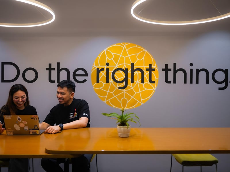 a person and person sitting at a table with a laptop