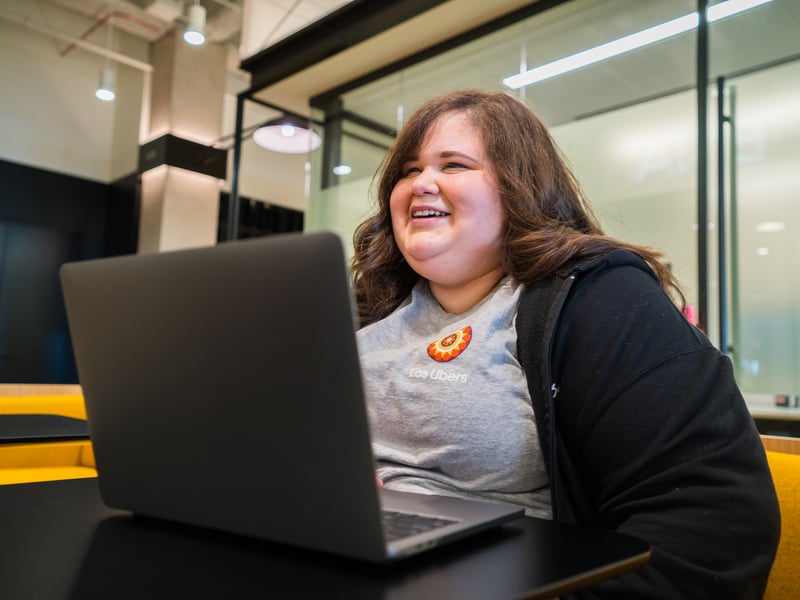 a person smiling at a laptop