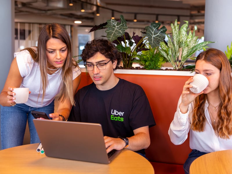 a group of people sitting at a table looking at a laptop