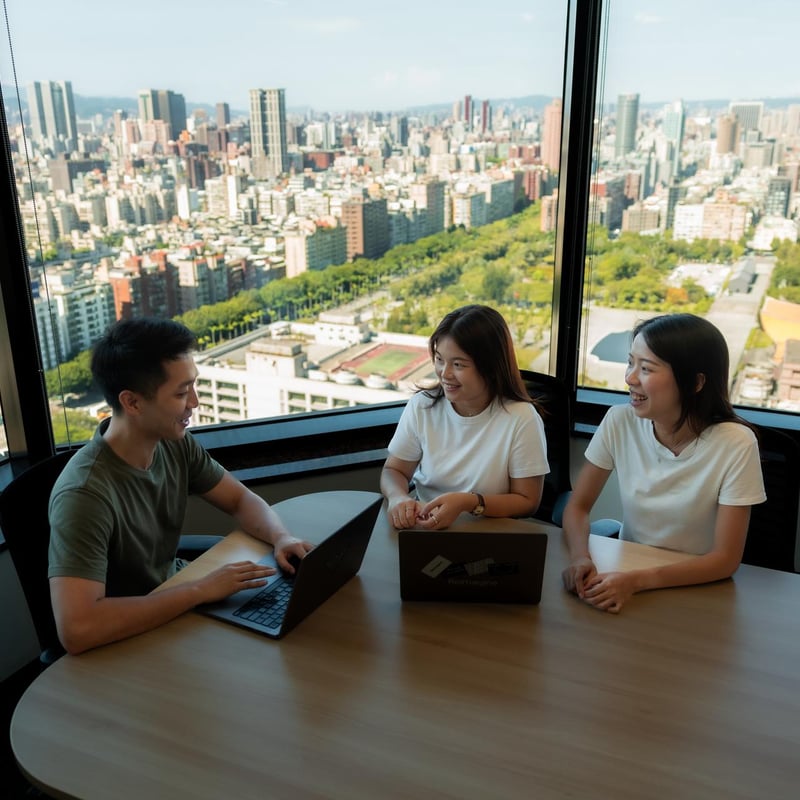 a group of people sitting at a table with laptops