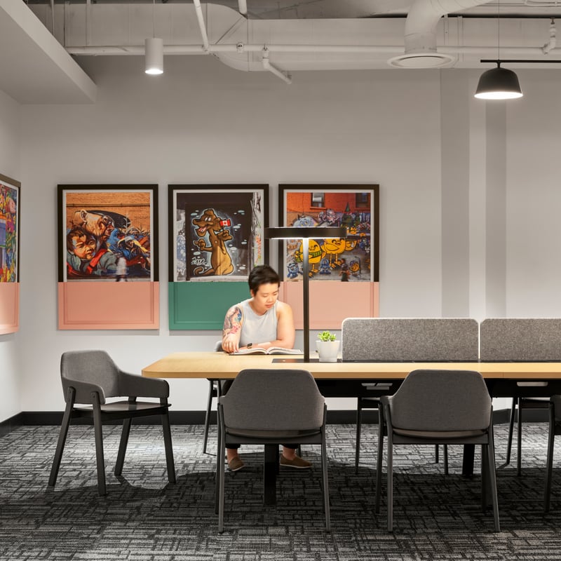 a person sitting at a table in a room with art on the wall