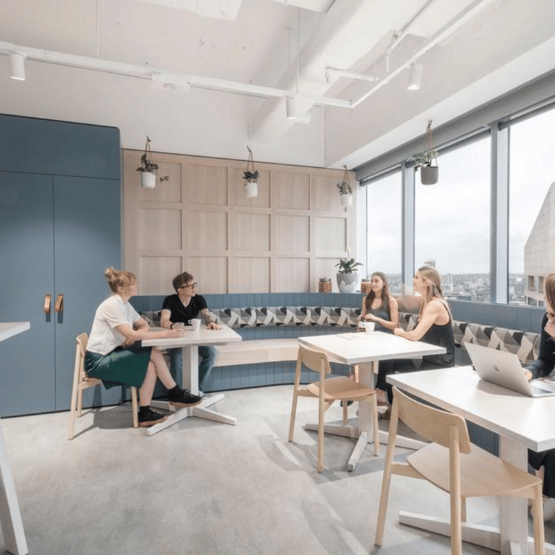 a group of people sitting at tables in a room with windows