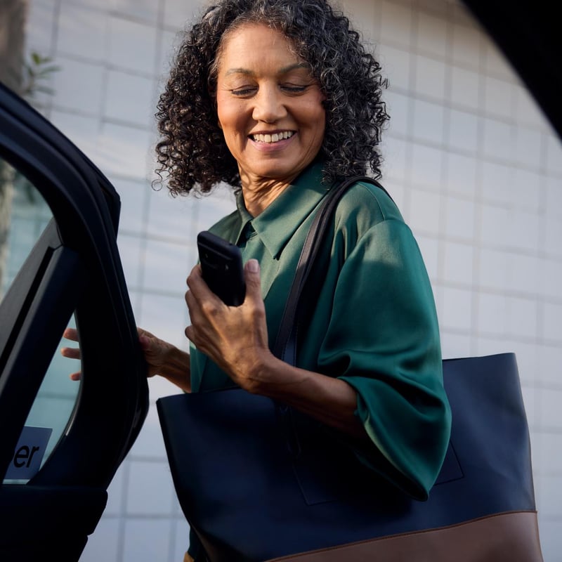a person holding a phone and looking at her car door