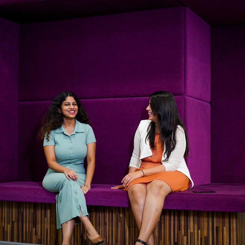 two women sitting on a purple bench