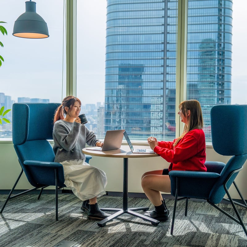 two women sitting at a table with a laptop