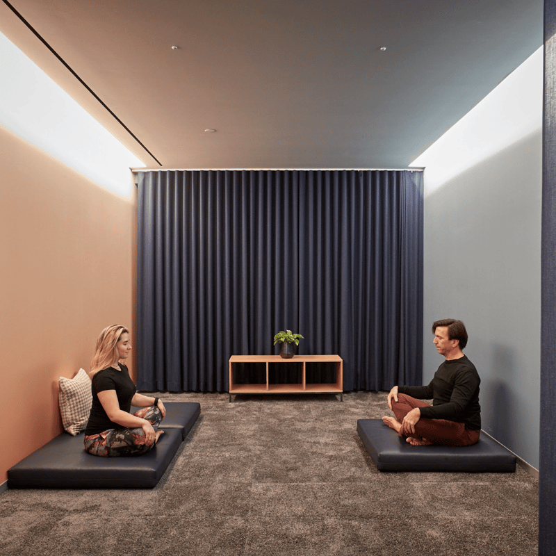 a person and person sitting on pillows in a room with curtains