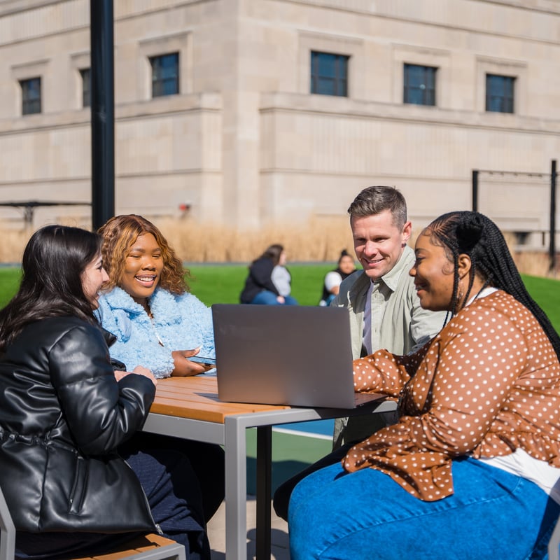 a group of people sitting at a table with a laptop