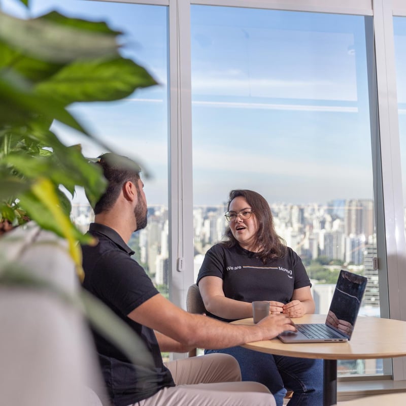 a person and person sitting at a table with a laptop