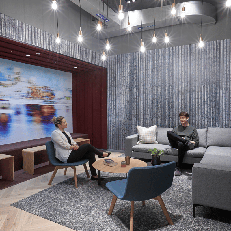 a person and person sitting on a couch in a room with a wall and a picture