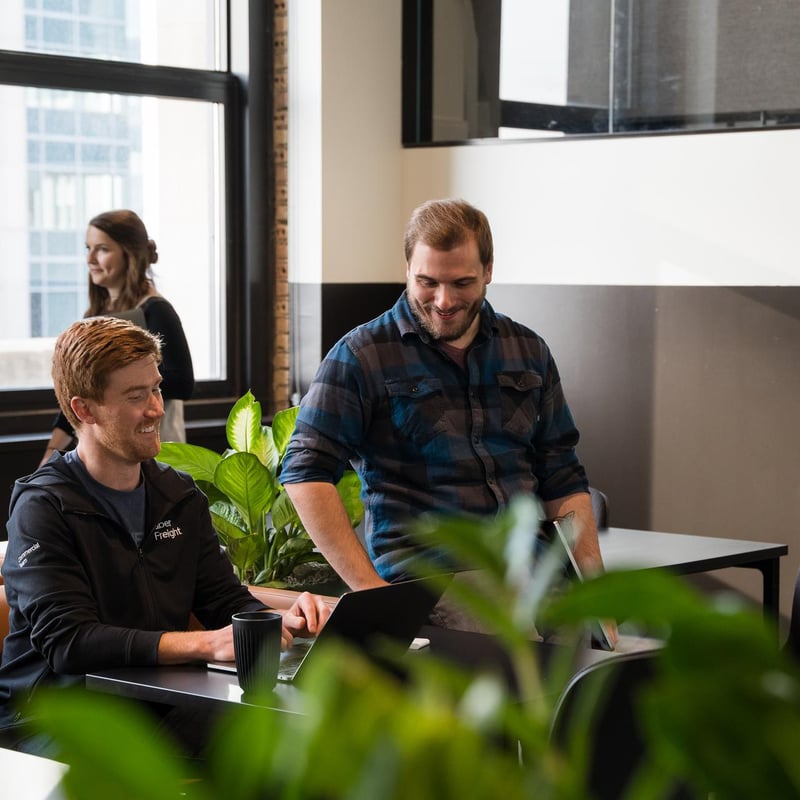 a group of men sitting at a table with a laptop