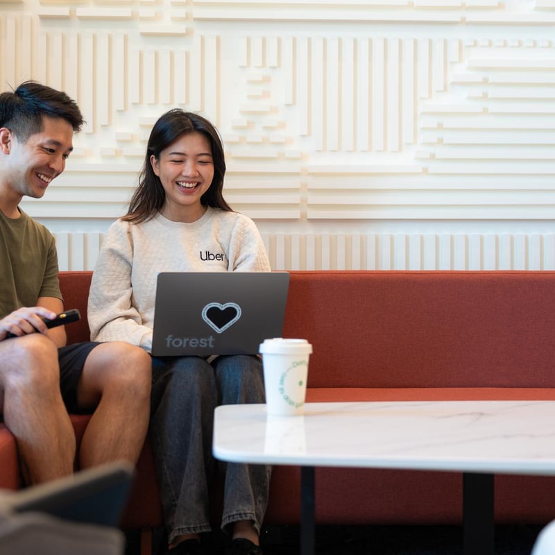 a person and person sitting on a couch with a laptop