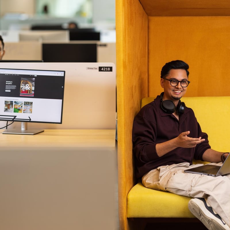 a person sitting on a yellow chair with a laptop