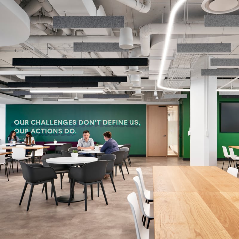 a group of people sitting at tables in a room with green walls