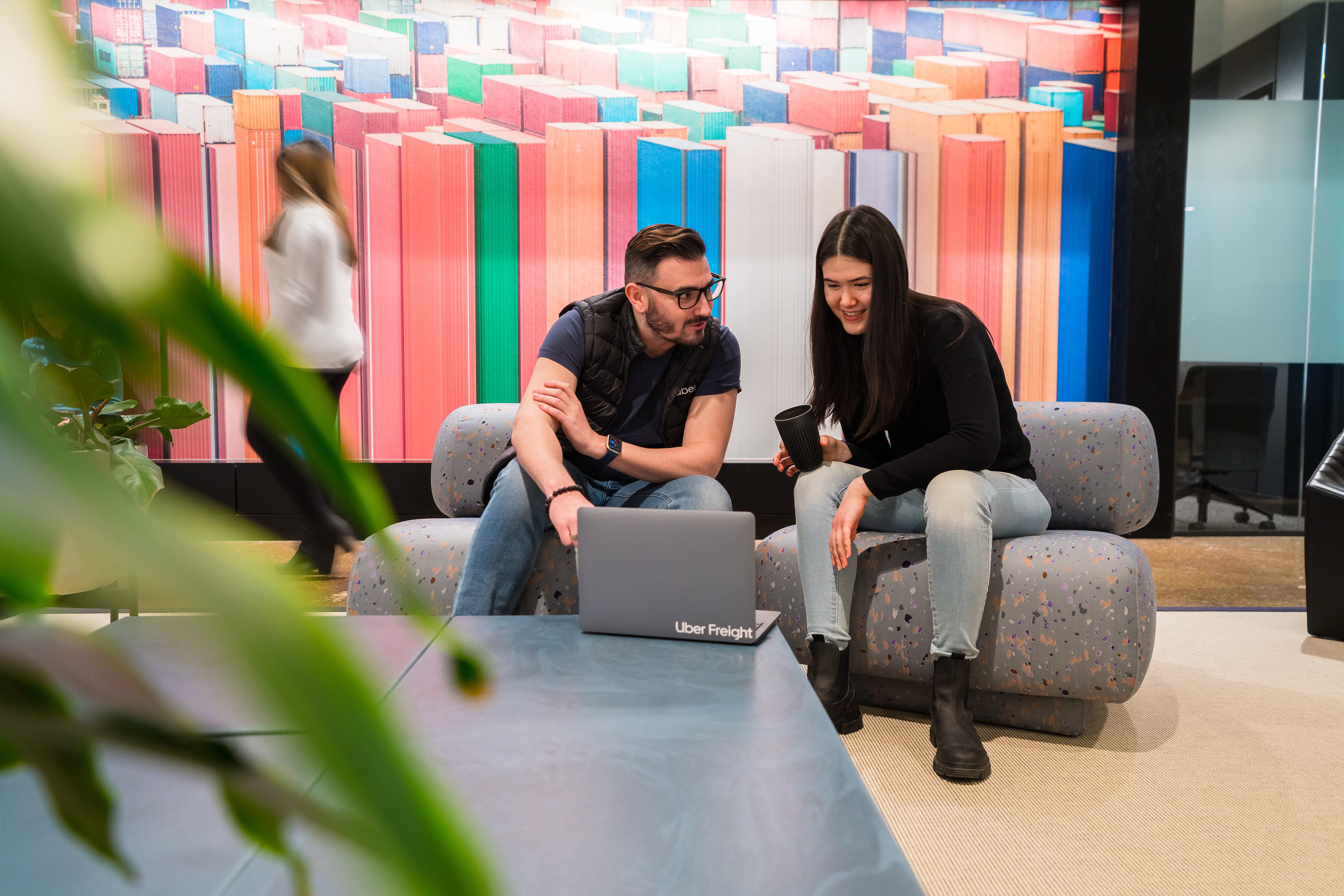 a person and person sitting on couches looking at a laptop