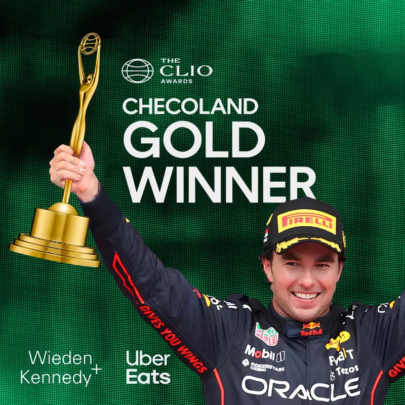 a person in a race car uniform holding a trophy