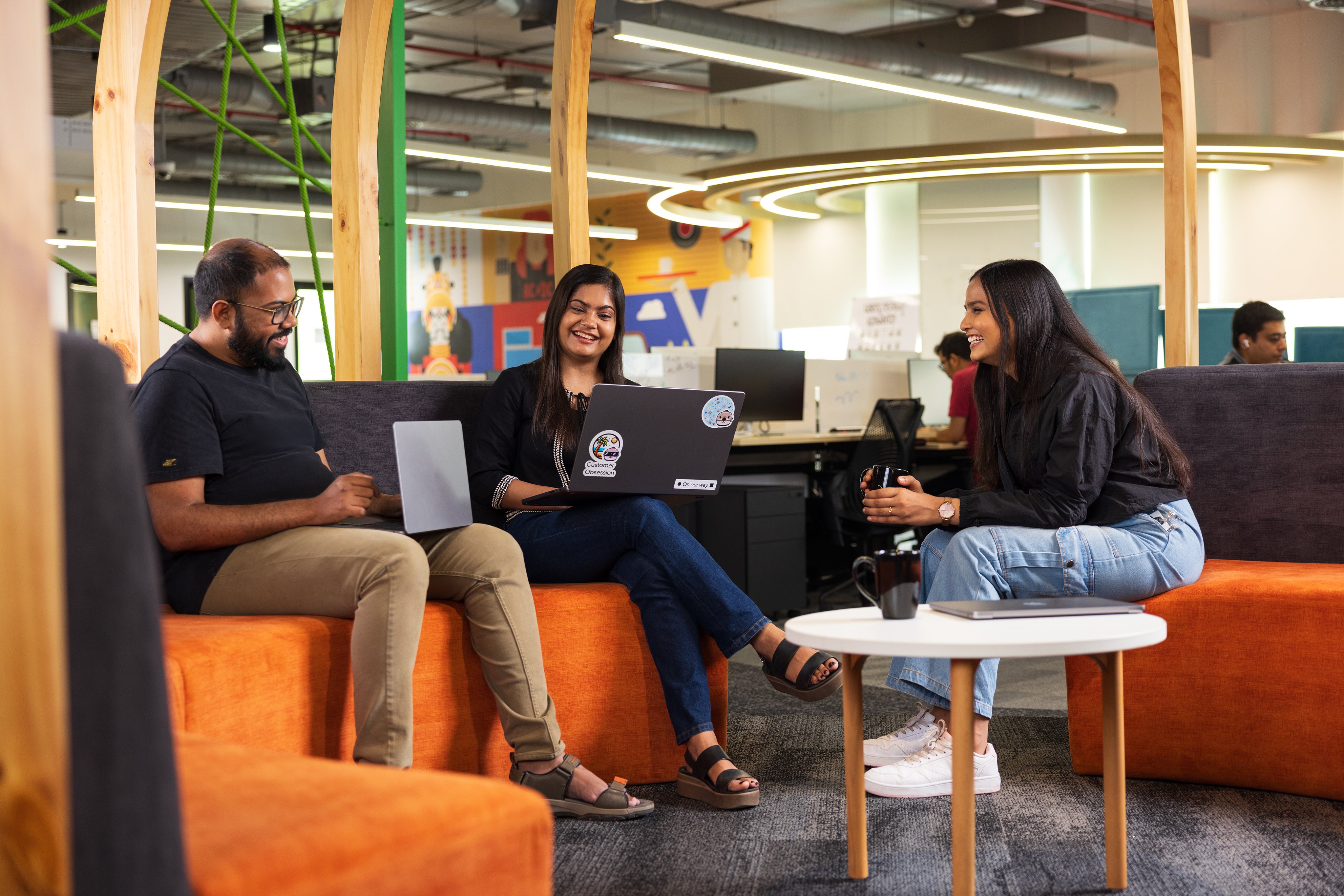 a group of people sitting on a couch with laptops